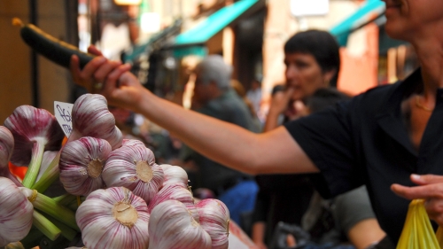 street food shoppers at a food market, with bulbs of garlic in the foreground