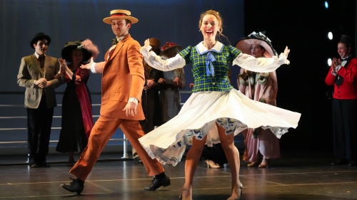 Performer twirling around in dress while others on stage dance also